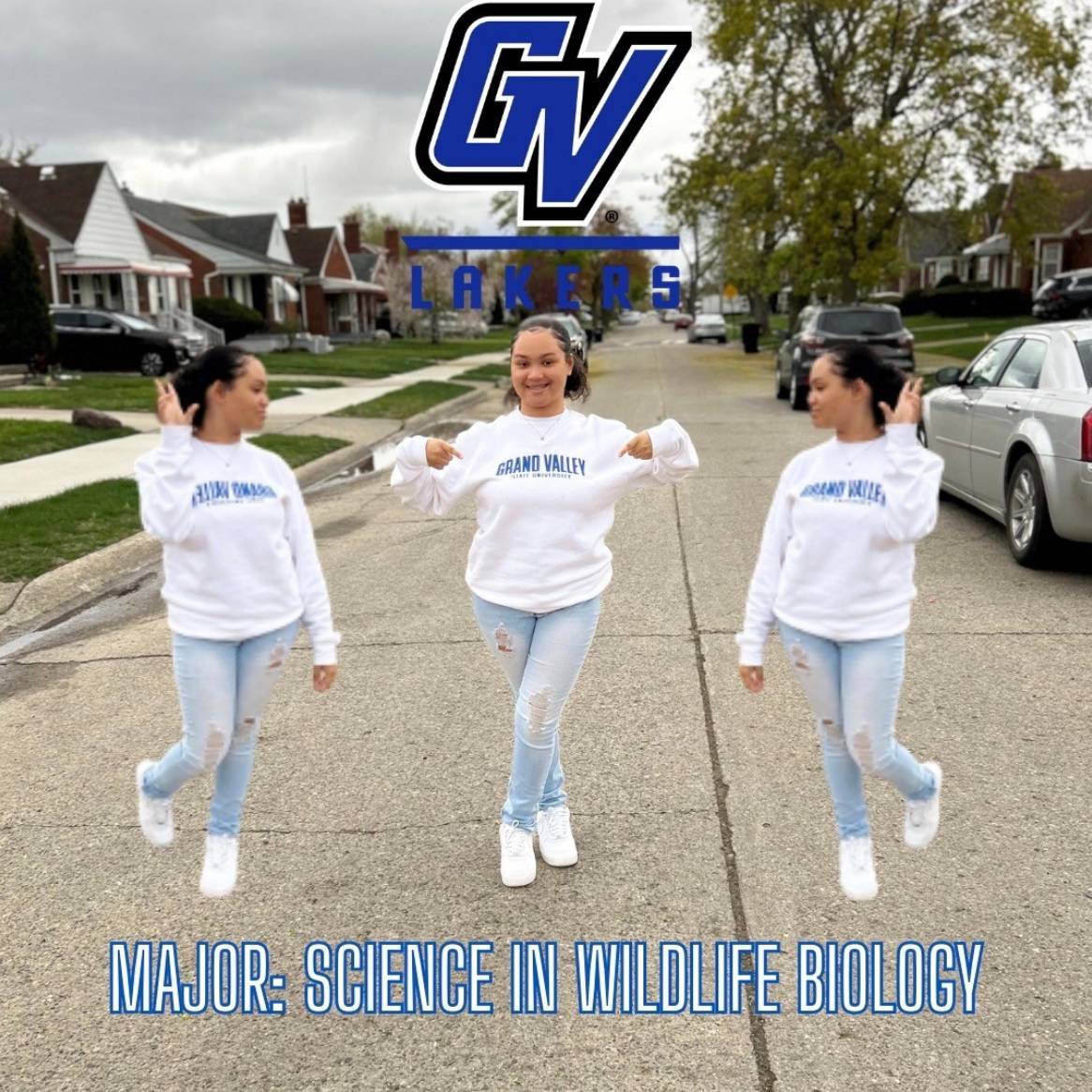 student wearing gvsu sweatshirt pointing to it on neighborhood street